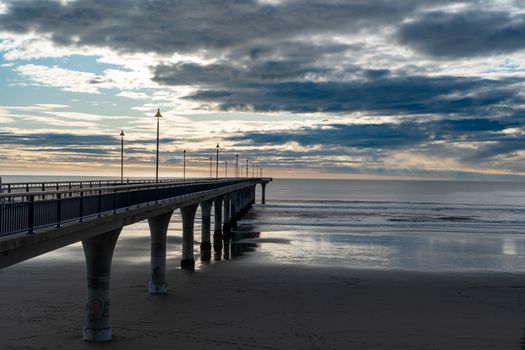 Serene sunset at New Brighton Pier in Christchurch with dramatic clouds and calm sea.