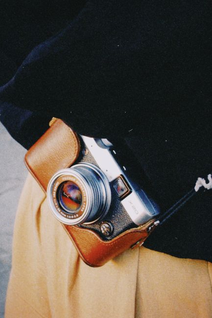 Close-up of a vintage analogue camera with a leather case, showcasing retro charm and style.