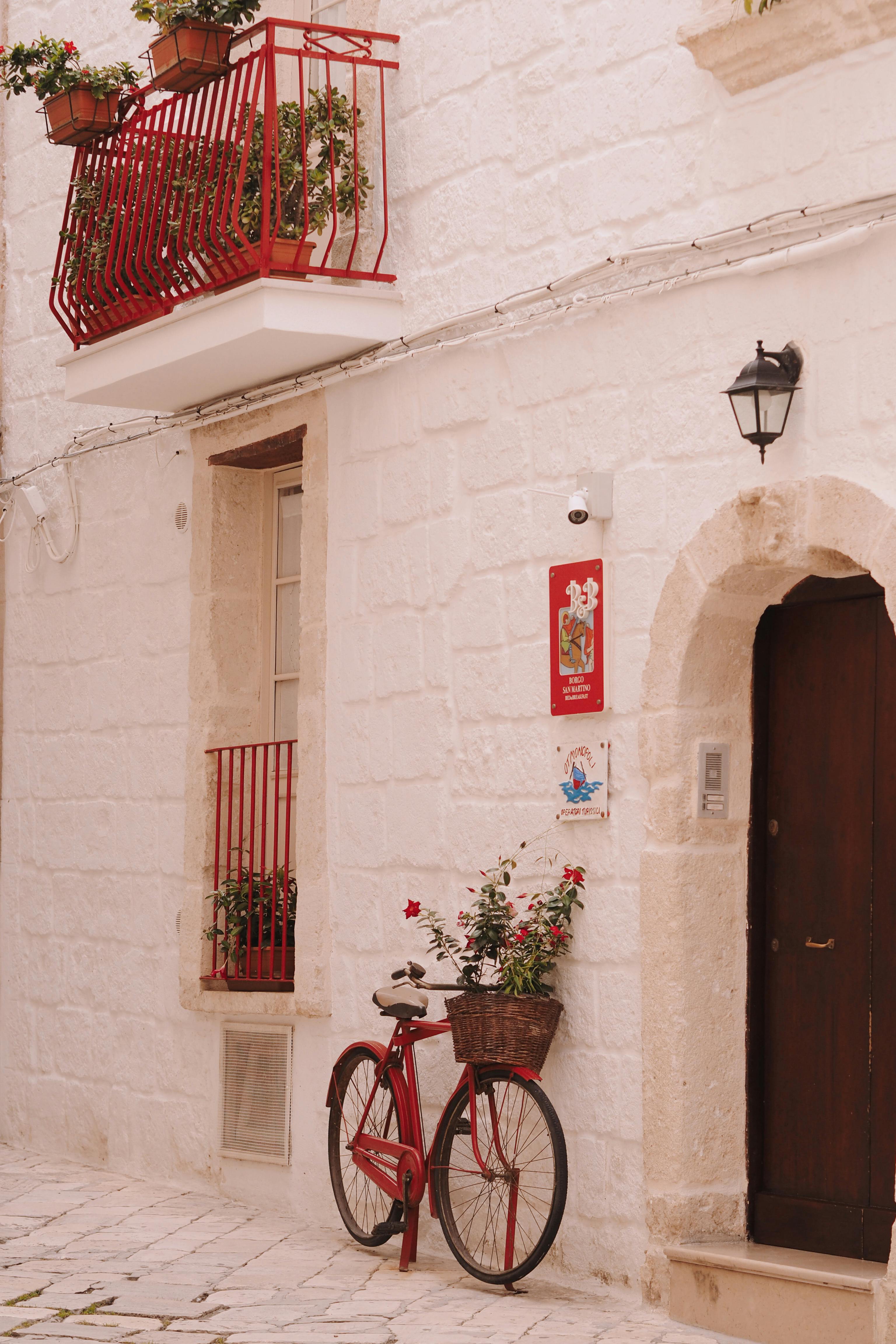 Vintage red bicycle against a cobblestone street facade in an old town setting.
