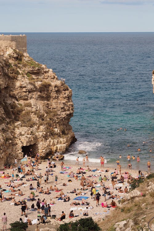 Tourist on Sandy Beach by Cliff