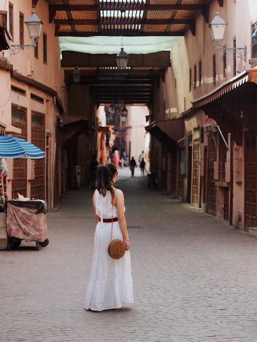 Woman in White Dress on Cobblestone Street in Town