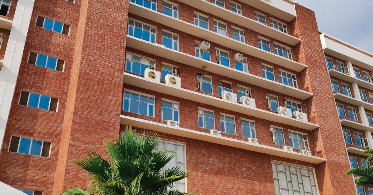 Photo by Gaming Iconic View of an academic building with palm trees and people in a sunny urban setting.