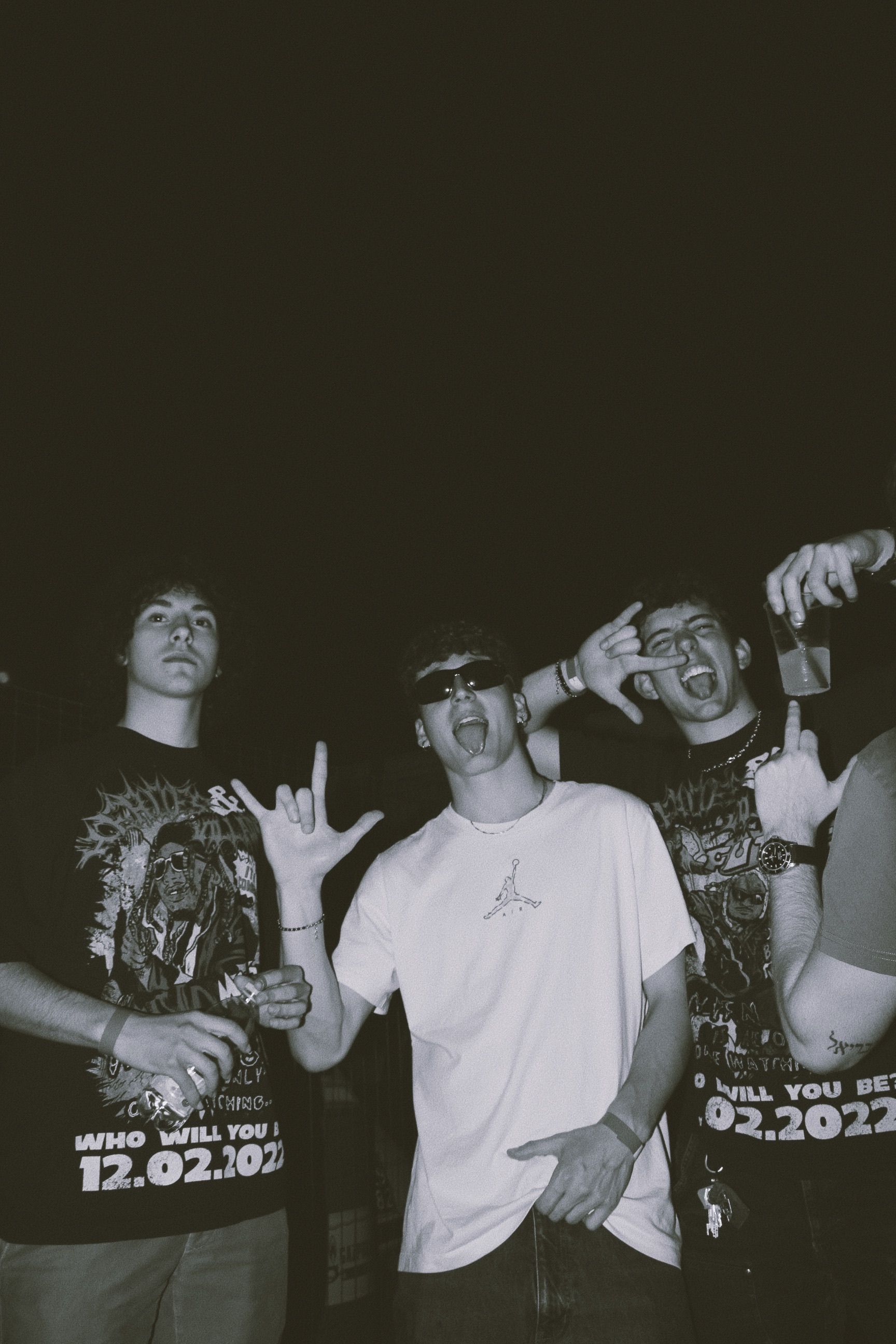 Three young adults posing enthusiastically at a nighttime gathering, showcasing youth culture