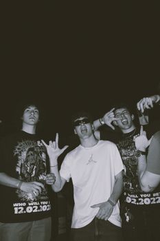 Three young adults posing enthusiastically at a nighttime gathering, showcasing youth culture