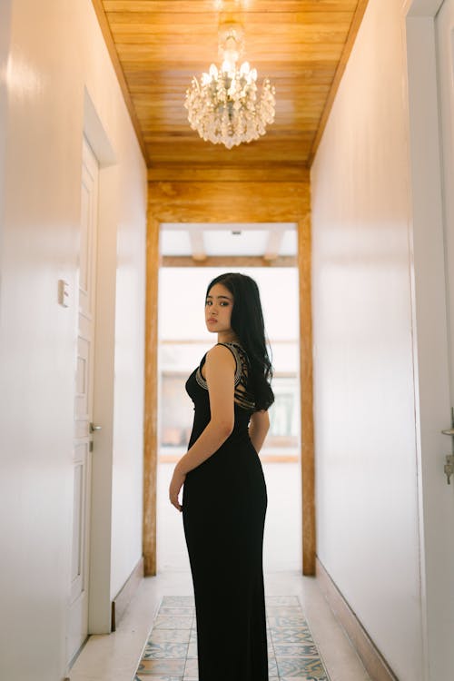 Young Woman in a Black Dress Standing in the Hallway 