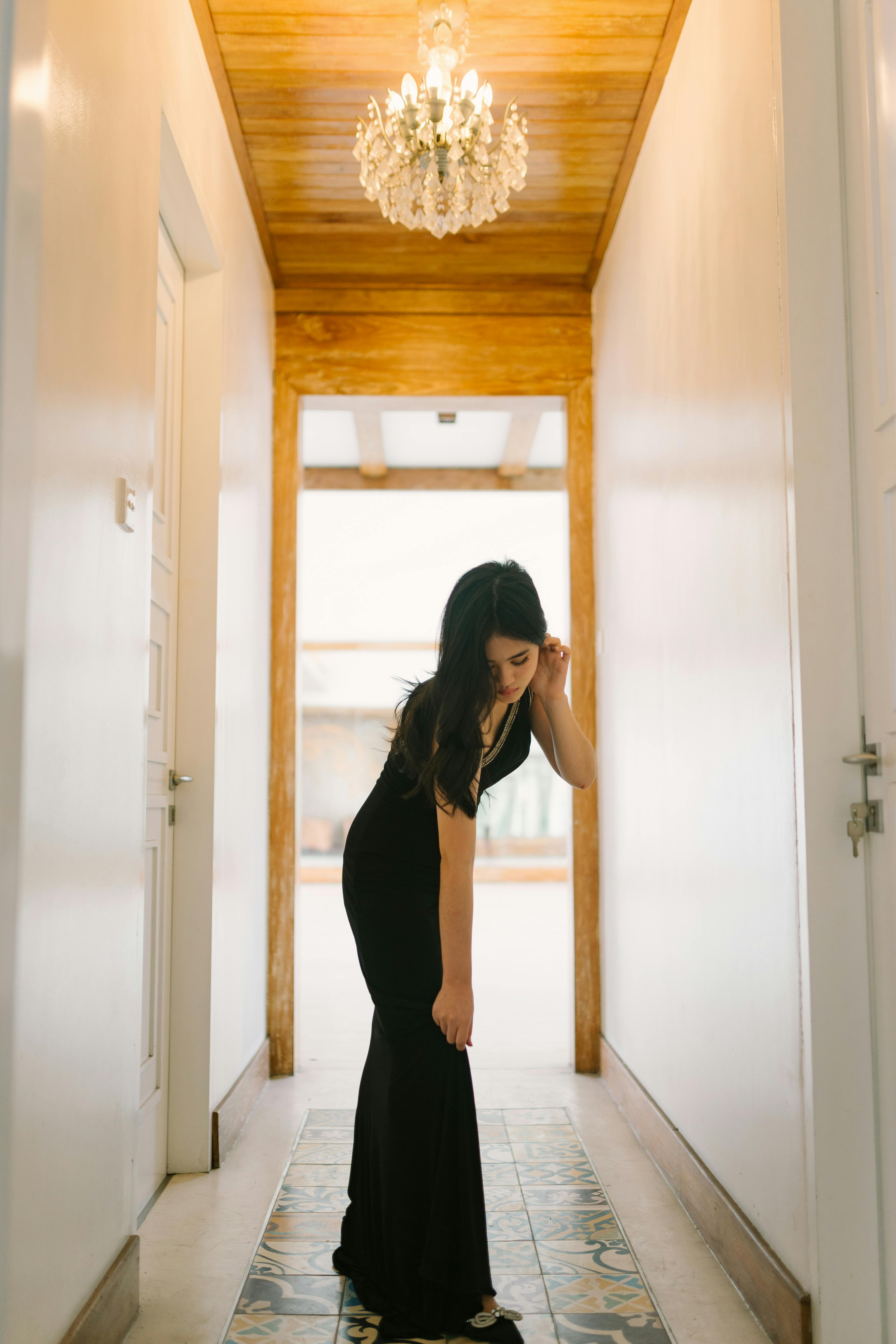 young woman in a black dress standing in the hallway