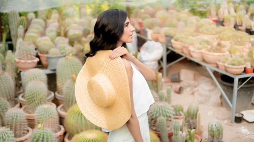Free Woman with straw hat in cactus-filled greenhouse, showcasing fashion and nature fusion. Stock Photo