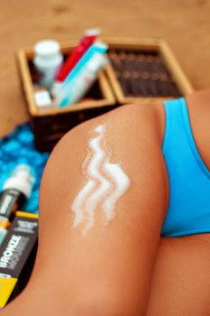Close-up of sunscreen applied on a woman's arm at the beach, emphasizing skincare and sun protection.