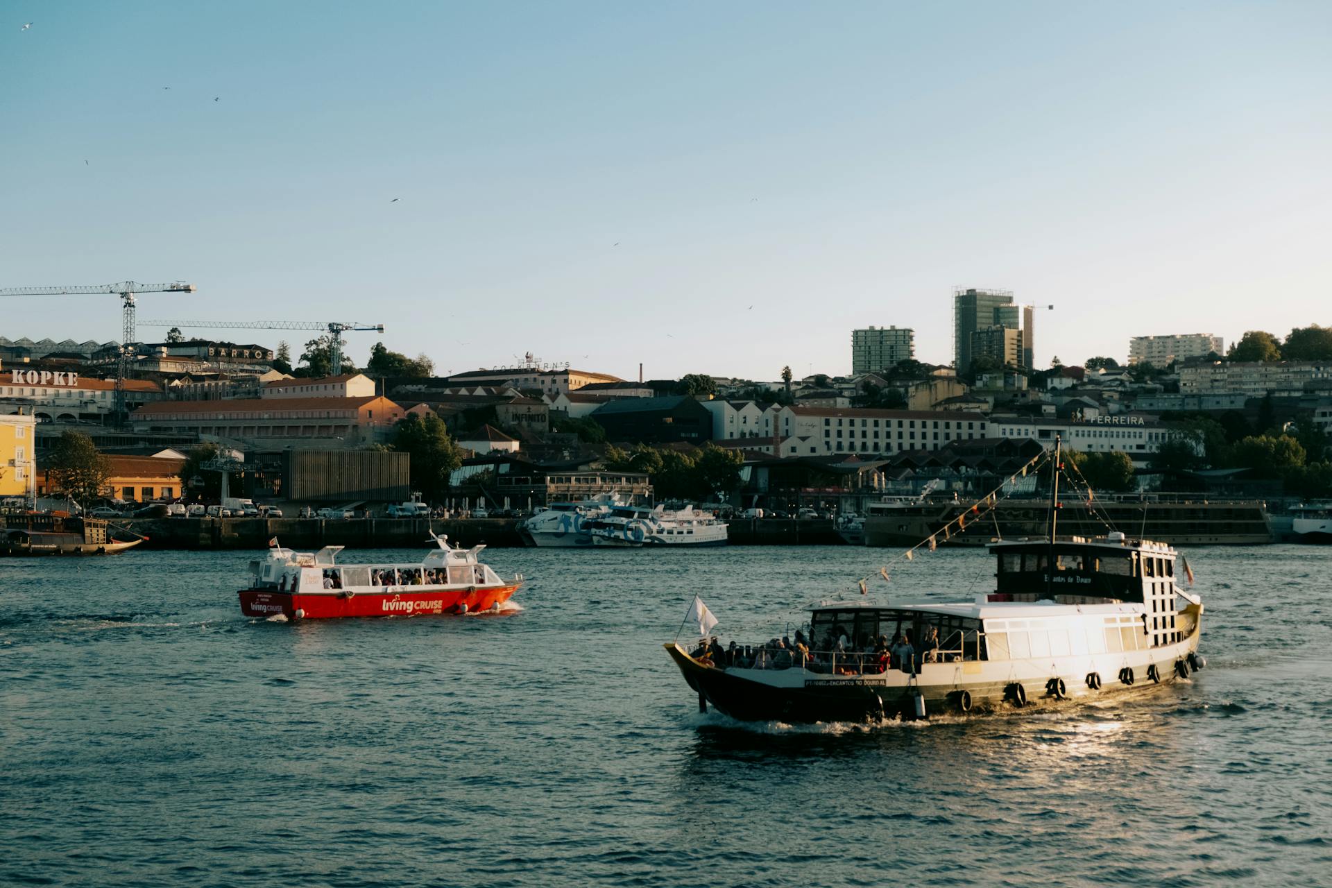 Boats cruising along a vibrant urban waterfront under a clear sky, perfect for travel enthusiasts.