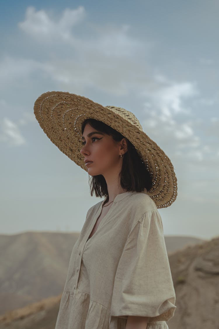 Young Woman In A Dress And Hat Posing Outside 