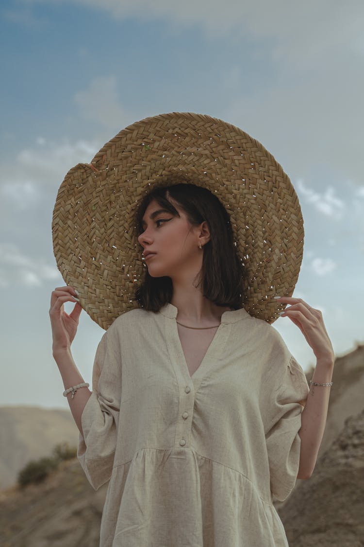 Young Woman In A Dress And Hat Posing Outside 