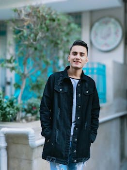 一个年轻人穿着休闲牛仔夹克，在户外微笑着享受阳光明媚的一天