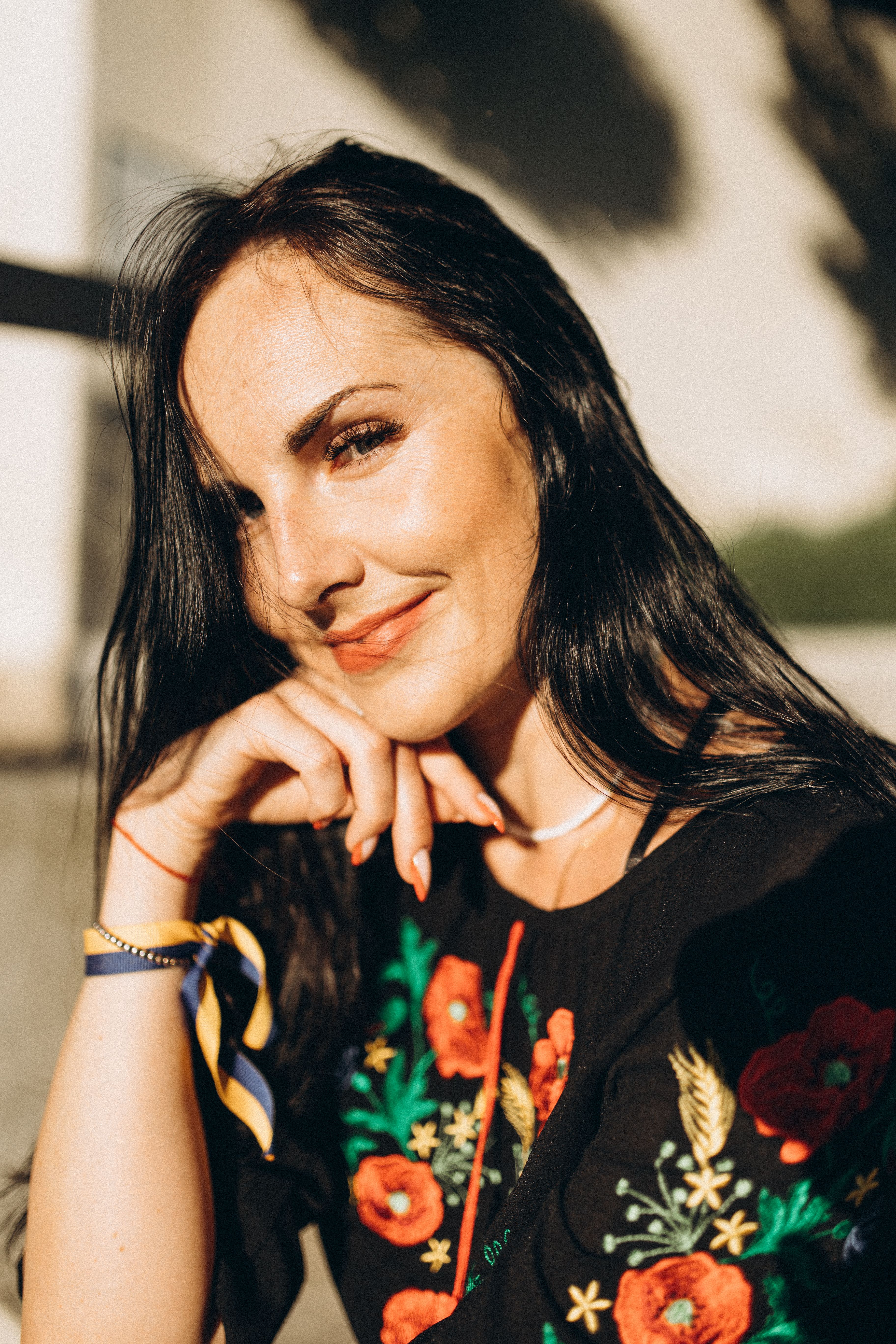 Elegant woman with long hair smiling in a sunny outdoor setting in Lviv, Ukraine.