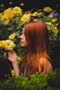 一名红发女子在花园里享受着黄玫瑰盛开的香味