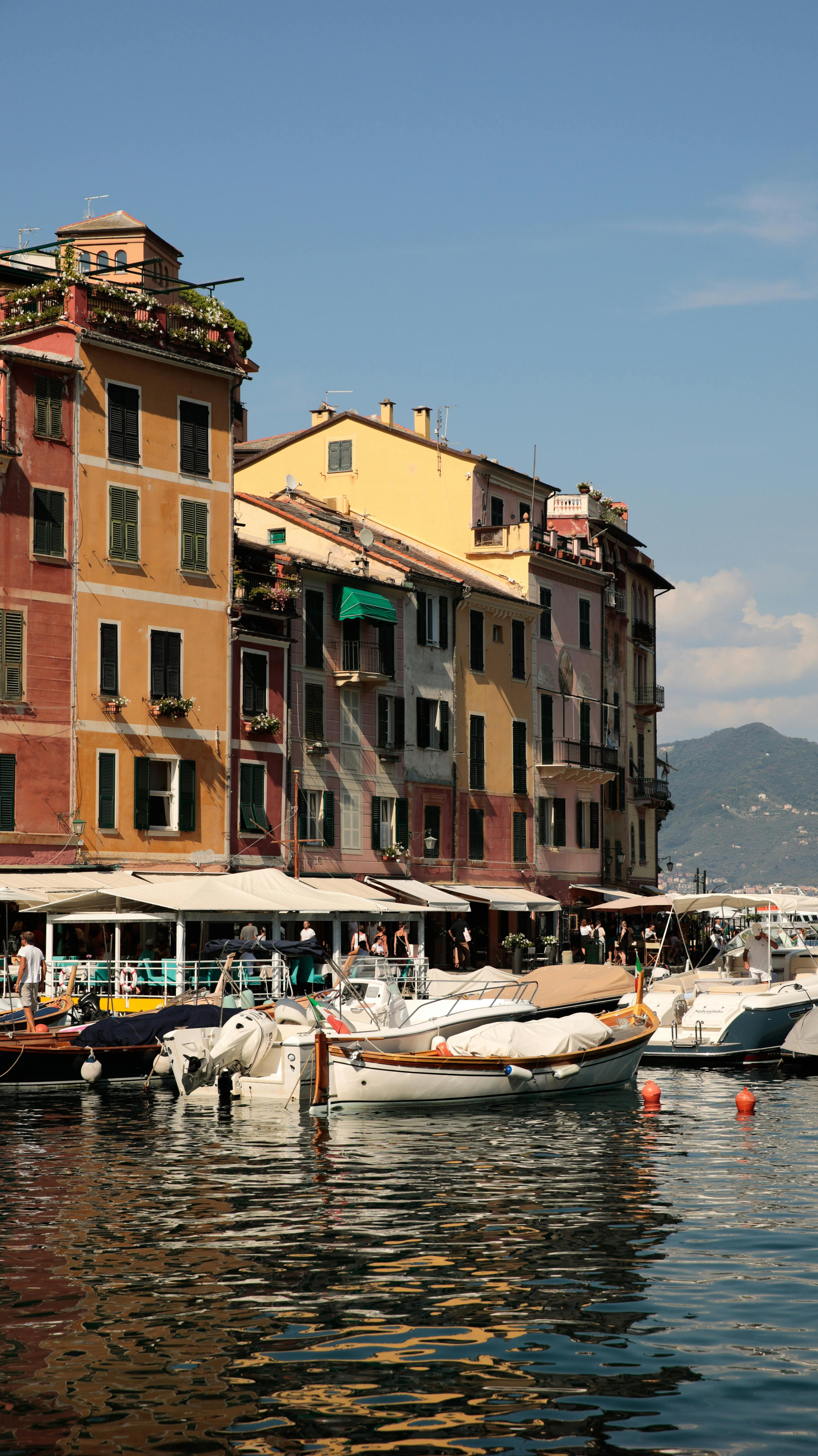 Colorful buildings by a harbor with moored boats under a clear sky.