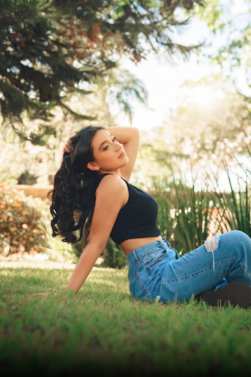 Young Woman Sitting on the Grass in the Garden 