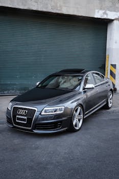 Modern black Audi sedan parked outside an industrial building, showcasing luxury design.