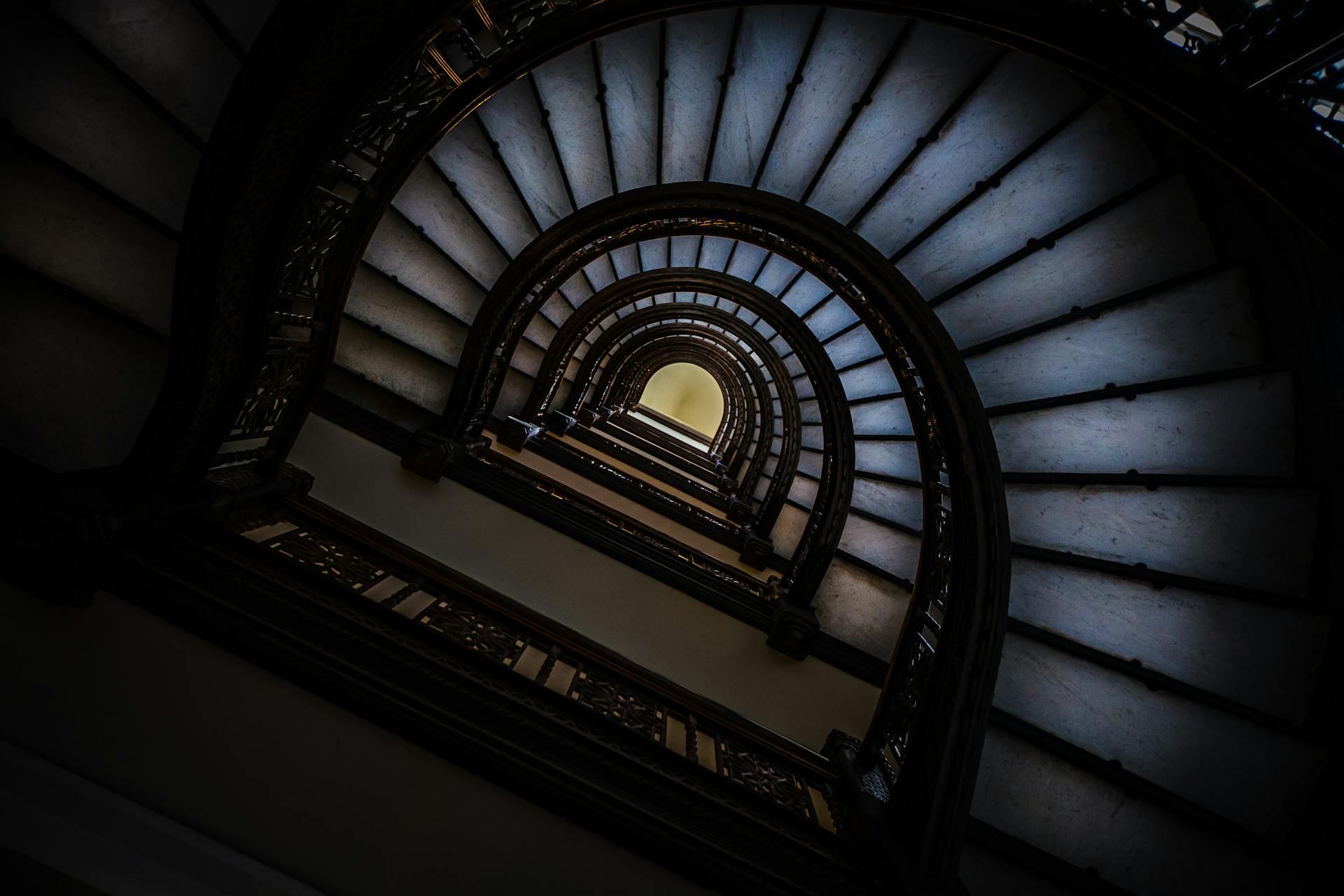 Artistic low-angle view of a spiral staircase with a focus on architectural design and perspective.