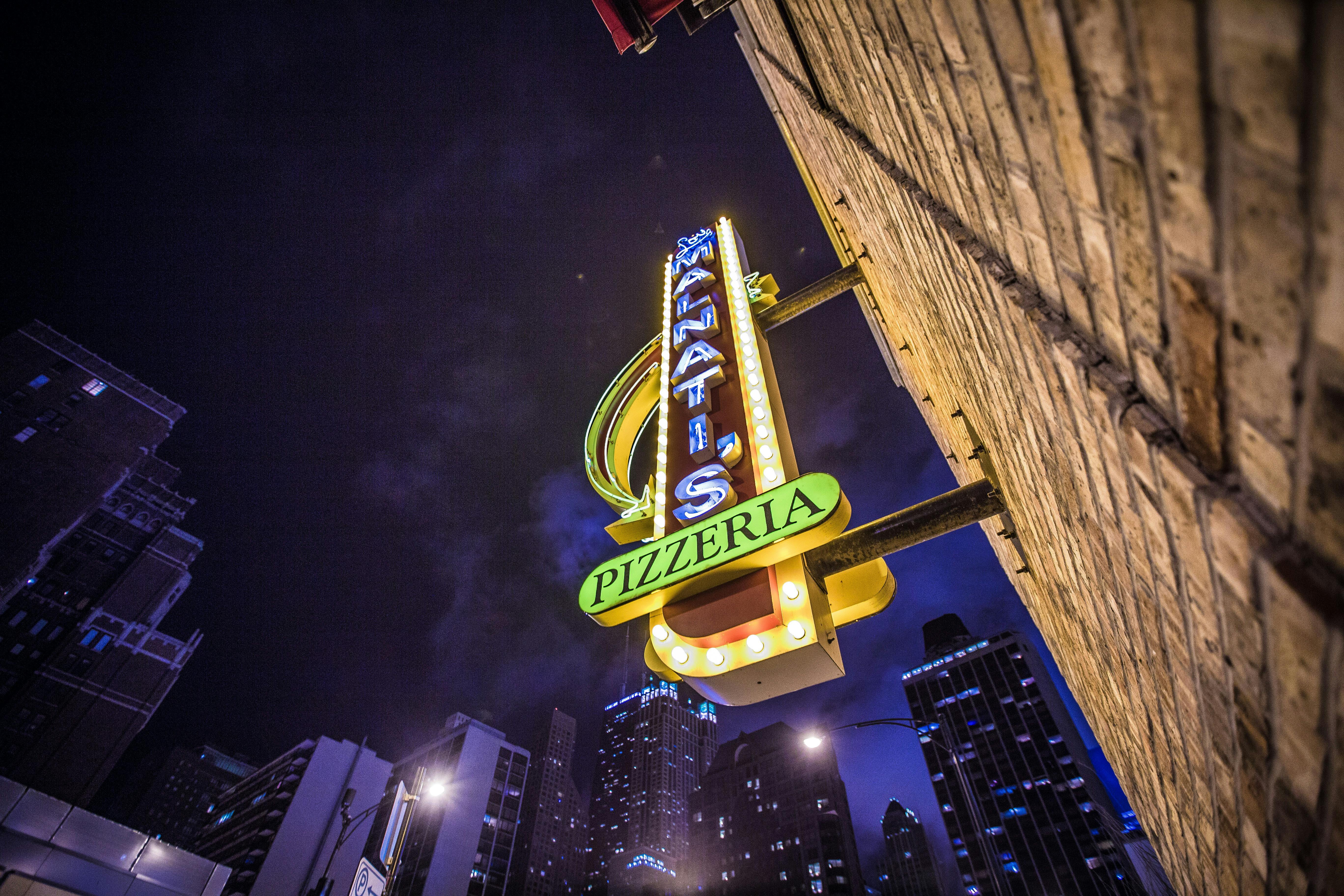 低角度拍摄的夜间城市天际线上，披萨店的标志在发光
