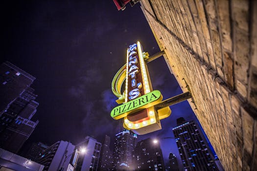 低角度拍摄的夜间城市天际线上，披萨店的标志在发光