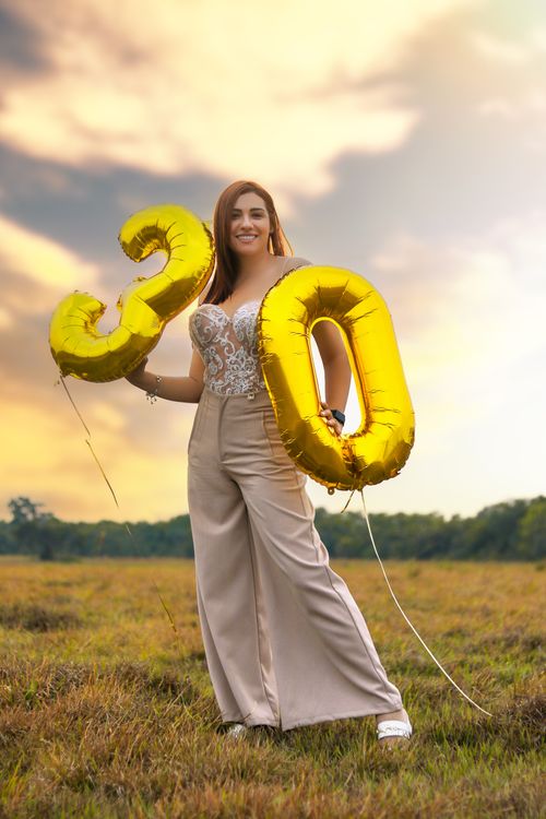Free Woman holding 30 balloons in a field, celebrating milestone birthday with style. Stock Photo
