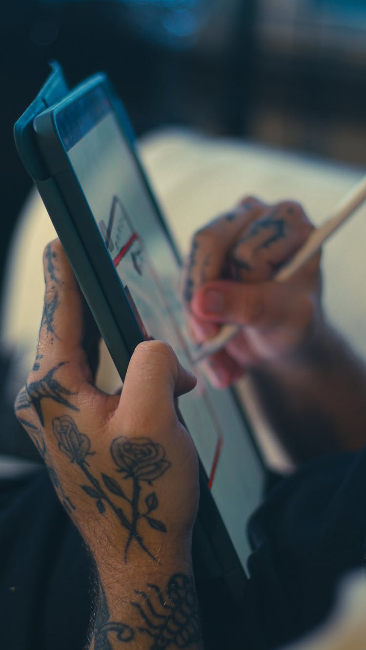 Tattooed Man Drawing On A Tablet Computer With A Stylus