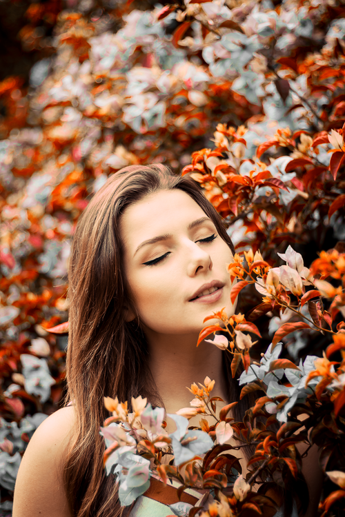 Free Peaceful young woman enjoying nature surrounded by colorful autumn leaves. Stock Photo