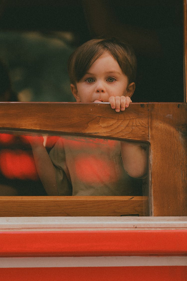 Child Looking From Behind A Wooden Balustrade