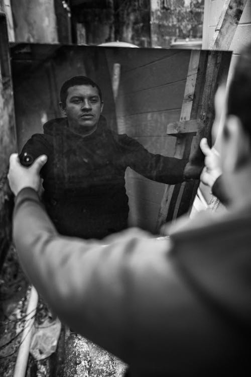 Monochrome Photo of Man Holding a Mirror