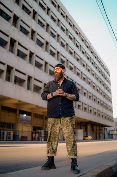 Stylish bearded man in urban setting with modern architecture background.