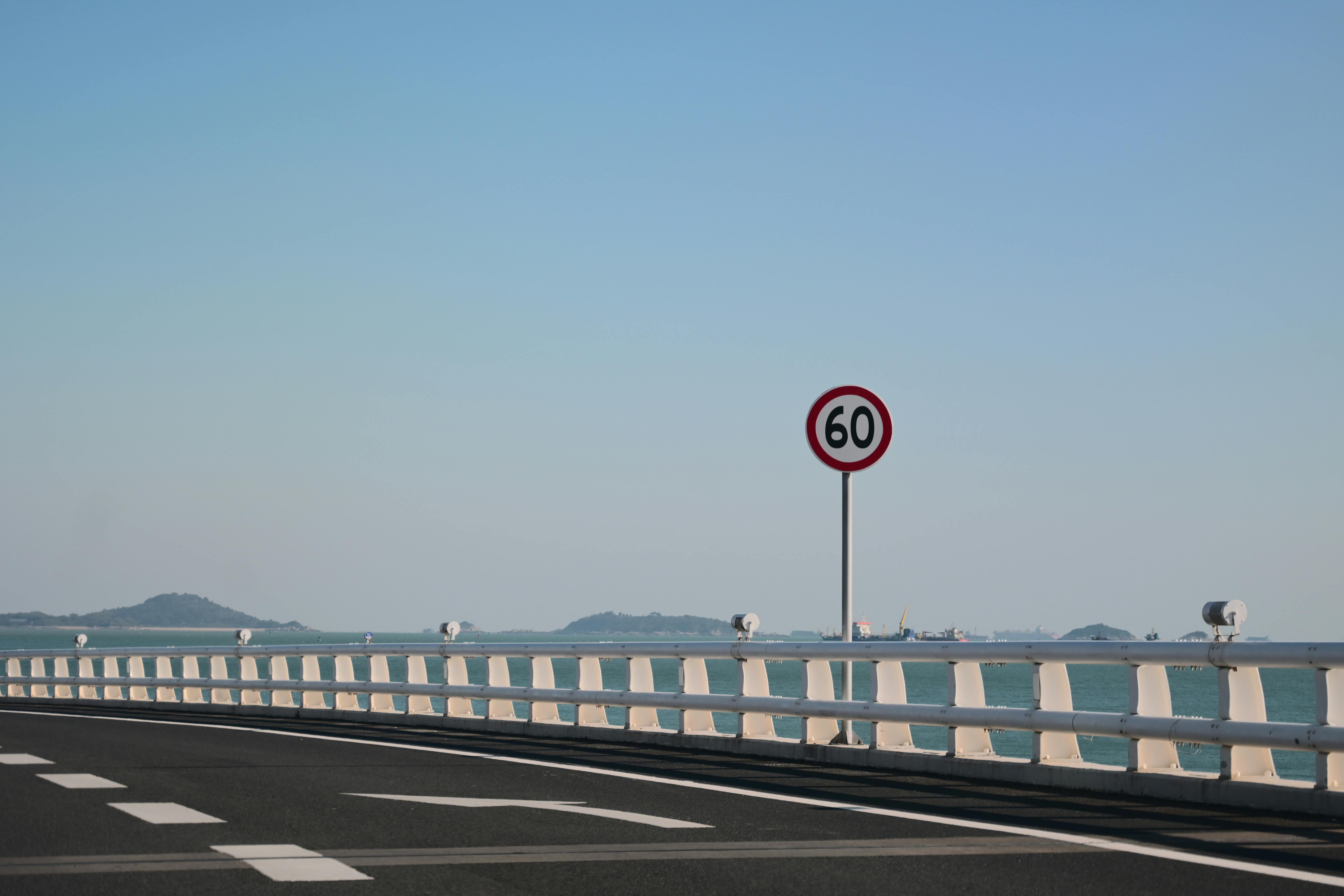 Photo of an Empty Bridge Road and a Speed Sign by the a Sea · Free