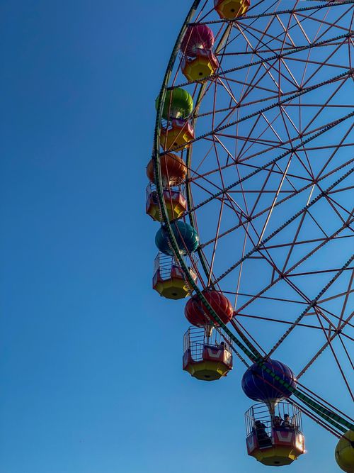 Free A vibrant ferris wheel soars against a clear blue sky, capturing the essence of amusement parks. Stock Photo