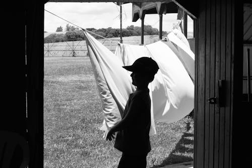 Silhouette of Boy Standing near Drying Fabrics