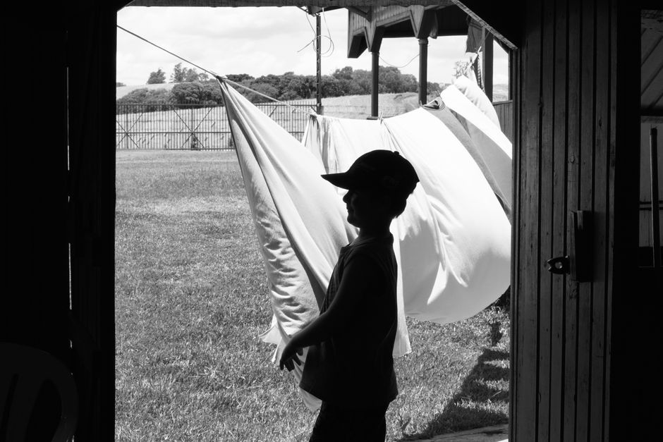 Silhouette of a child standing by drying fabrics on a rural farm in Carazinho, Brazil.