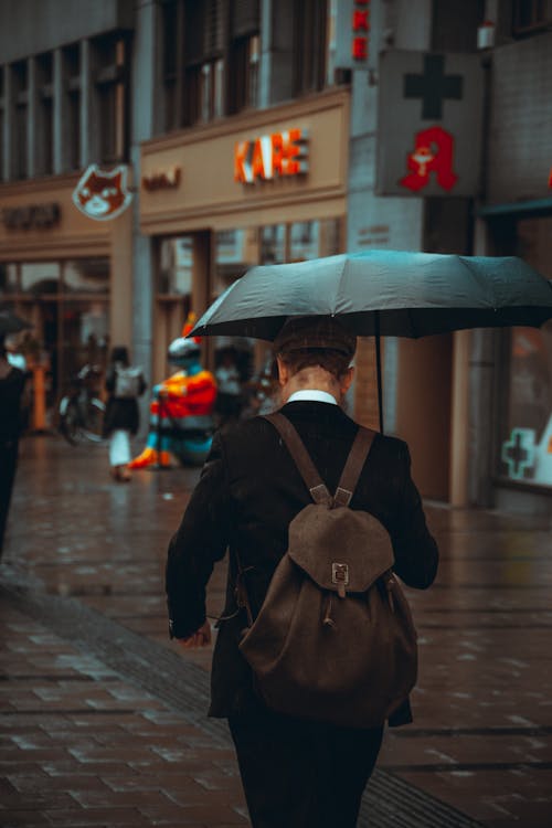 Man Walking with Umbrella and Backpack