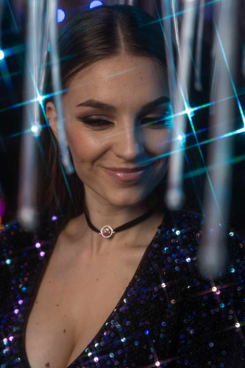Young woman in sequin dress smiling with twinkling lights