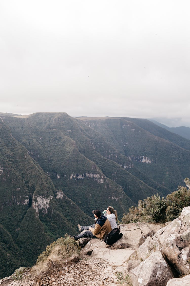 Couple Sitting On Edge Of Valley