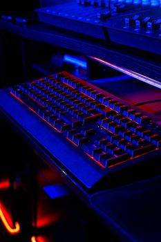 A gaming keyboard illuminated with red and blue LED lights on a dark desktop setup.