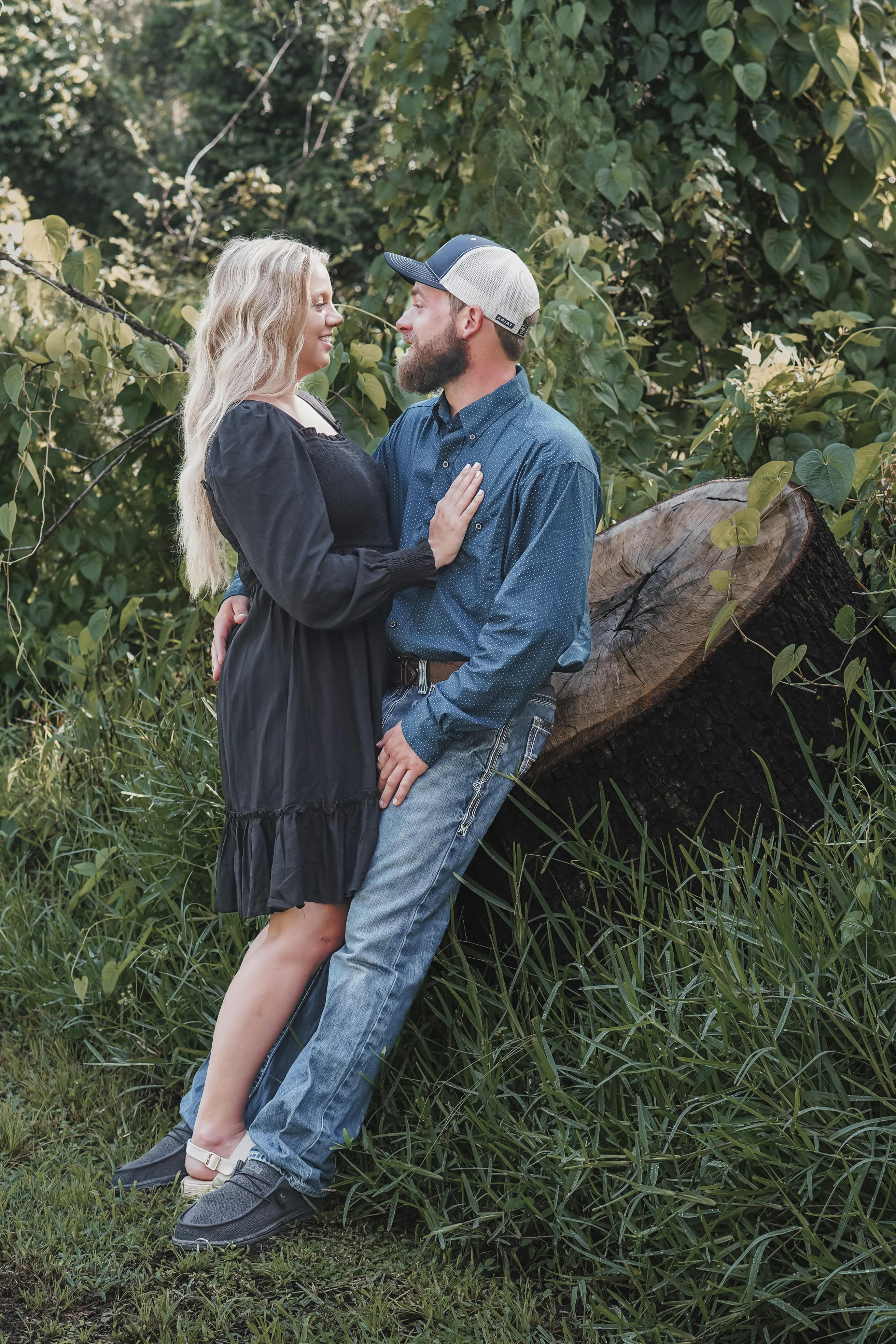An outdoor photo of a smiling couple lovingly embracing in a green park, exuding summer romance.