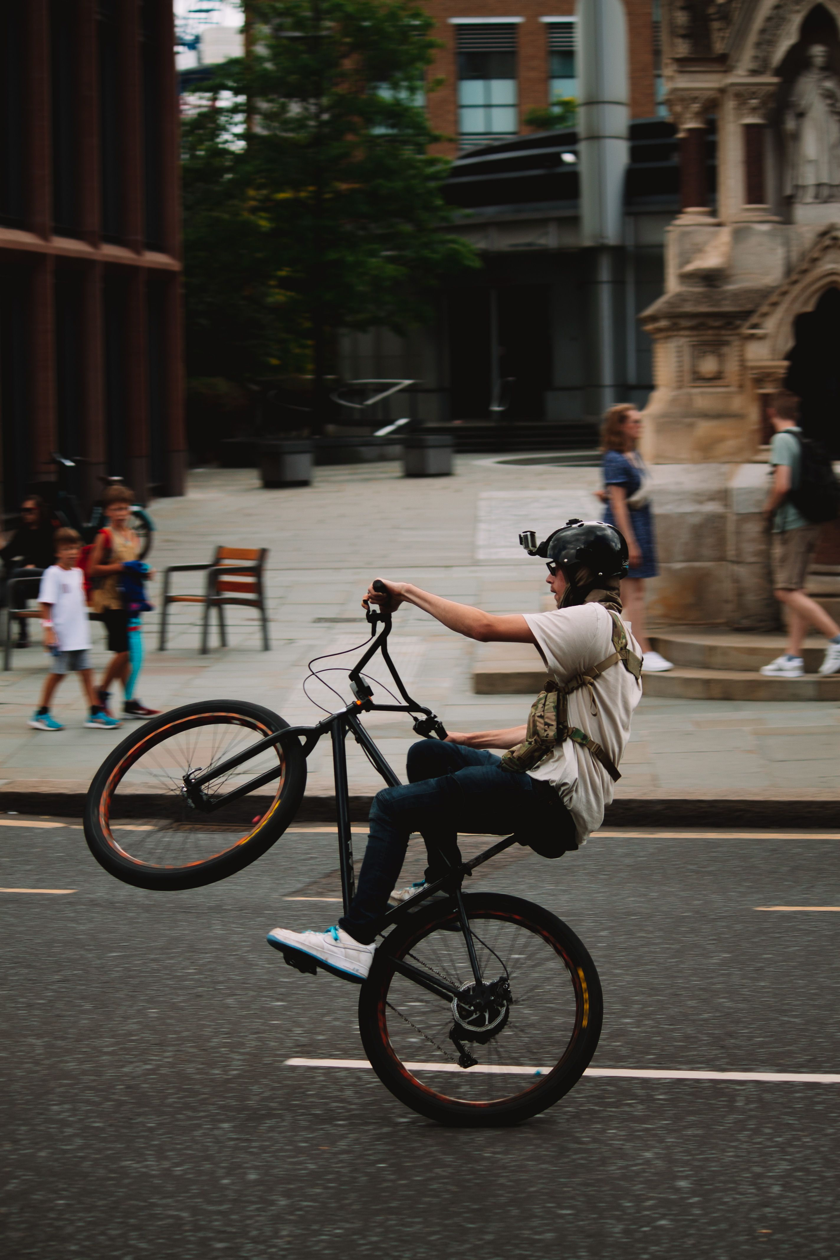 Urban cyclist performs a wheelie on a London street, showcasing balance and skill.