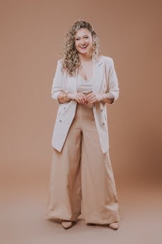 Stylish woman in beige attire posing in a studio, exuding elegance and charm.