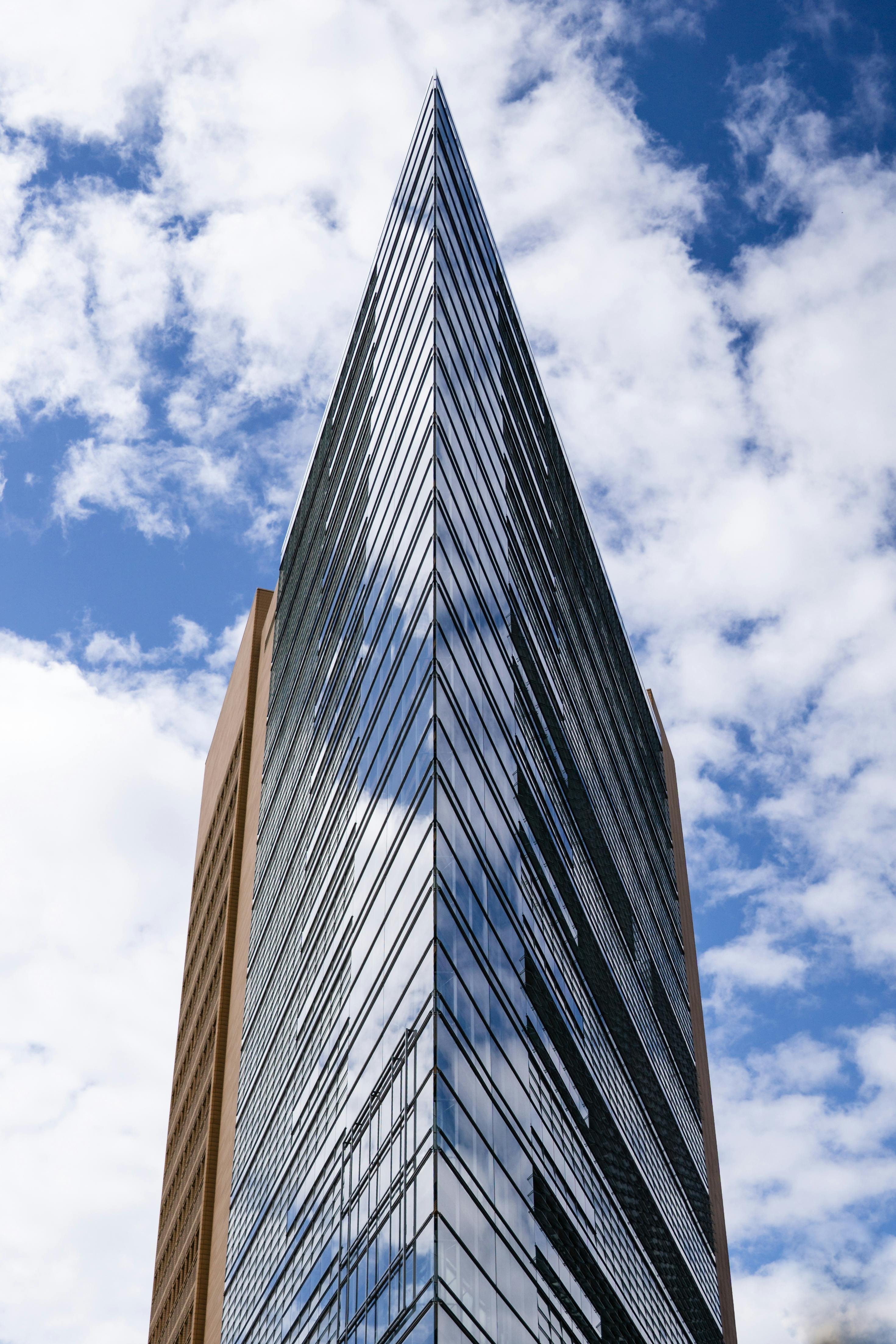 Vertical shot of modern high-rise building in Berlin featuring steel and glass architecture against a cloudy sky.