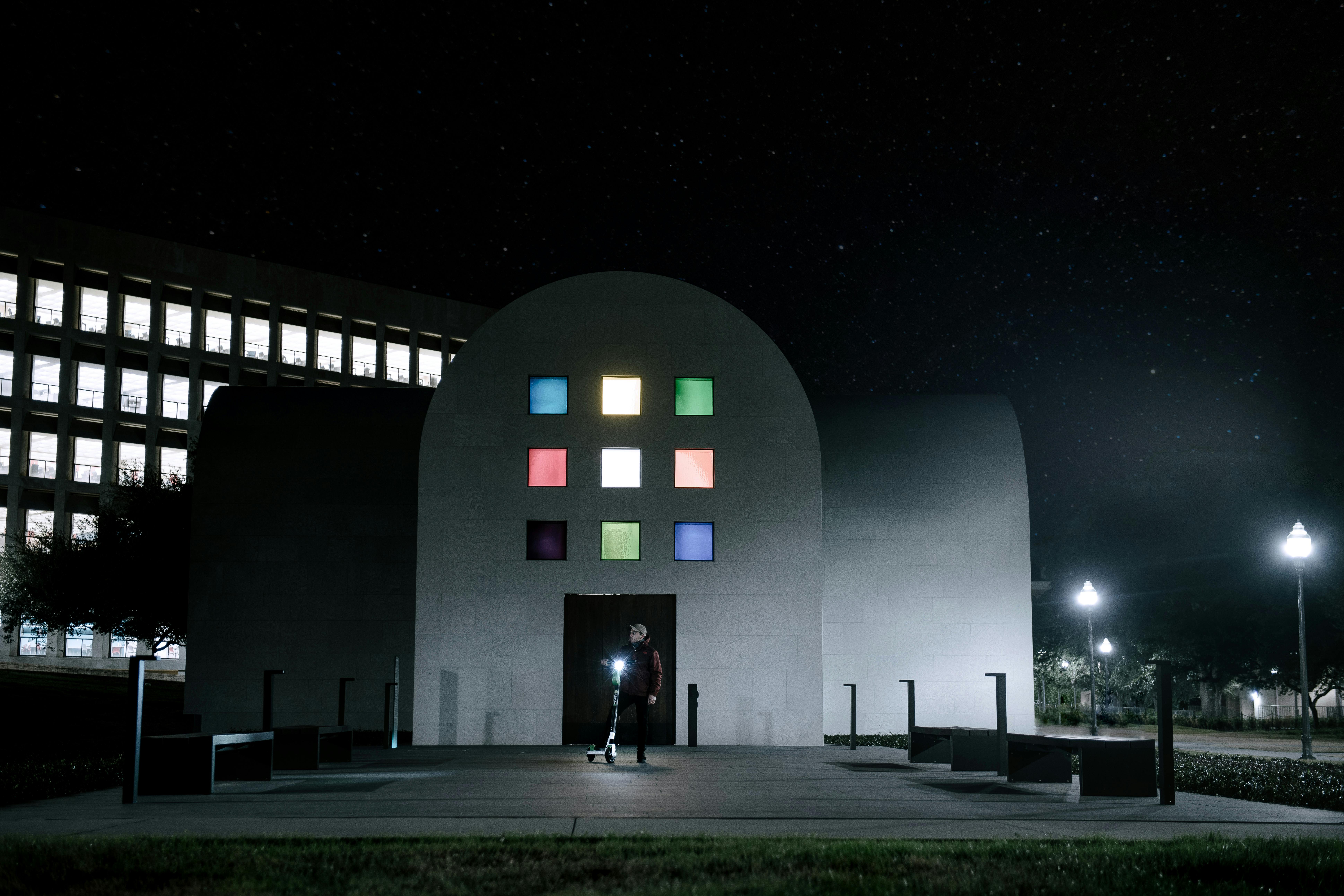 一个人站在一座有着彩色窗户、星光熠熠的现代建筑前