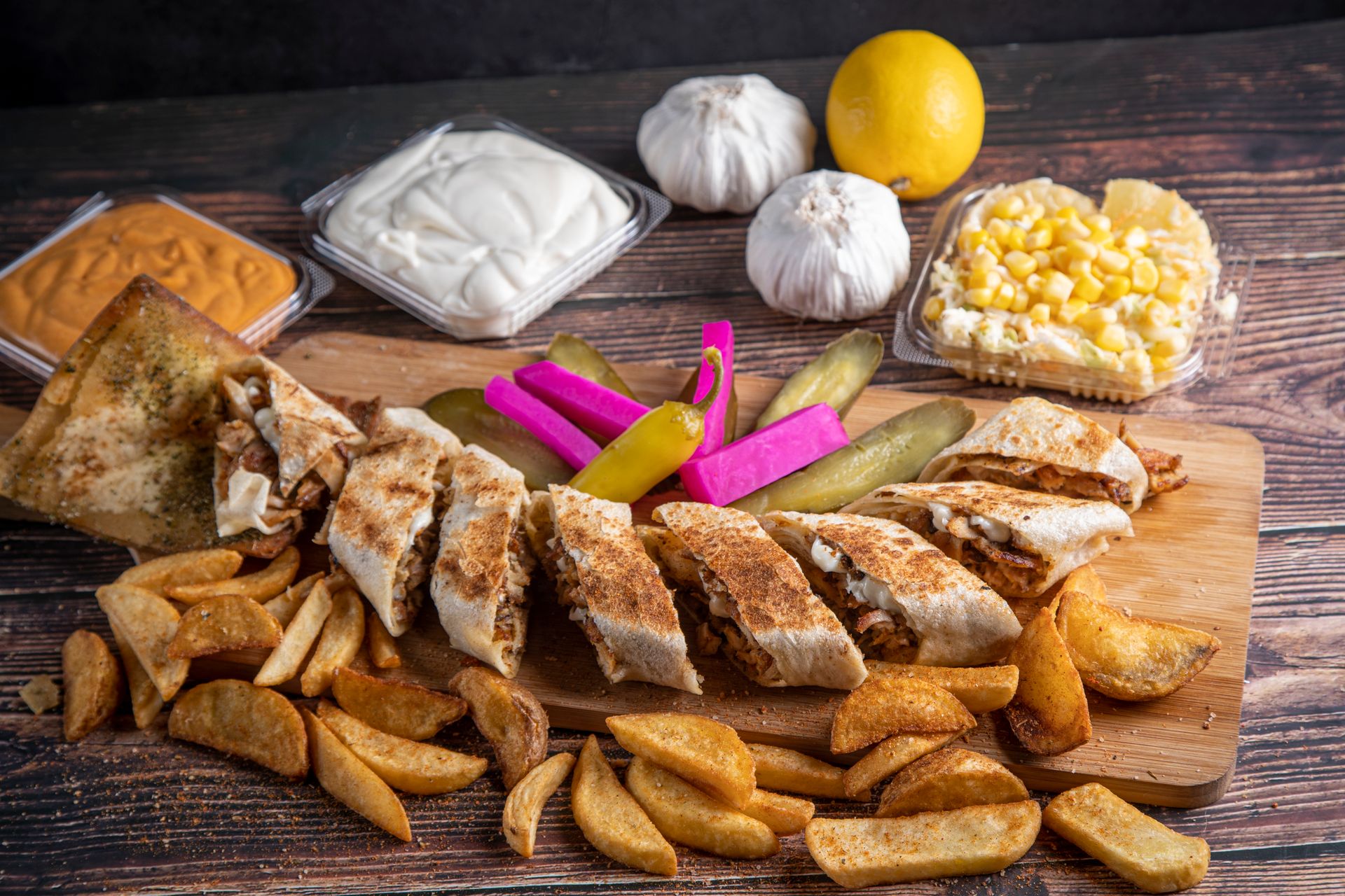 Delicious Middle Eastern spread featuring shawarma, garlic, dips, and fresh vegetables on a rustic table.