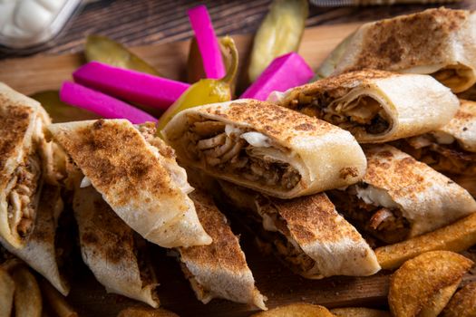 Close-up of delicious shawarma wraps served with vibrant pickled vegetables and crispy fries.