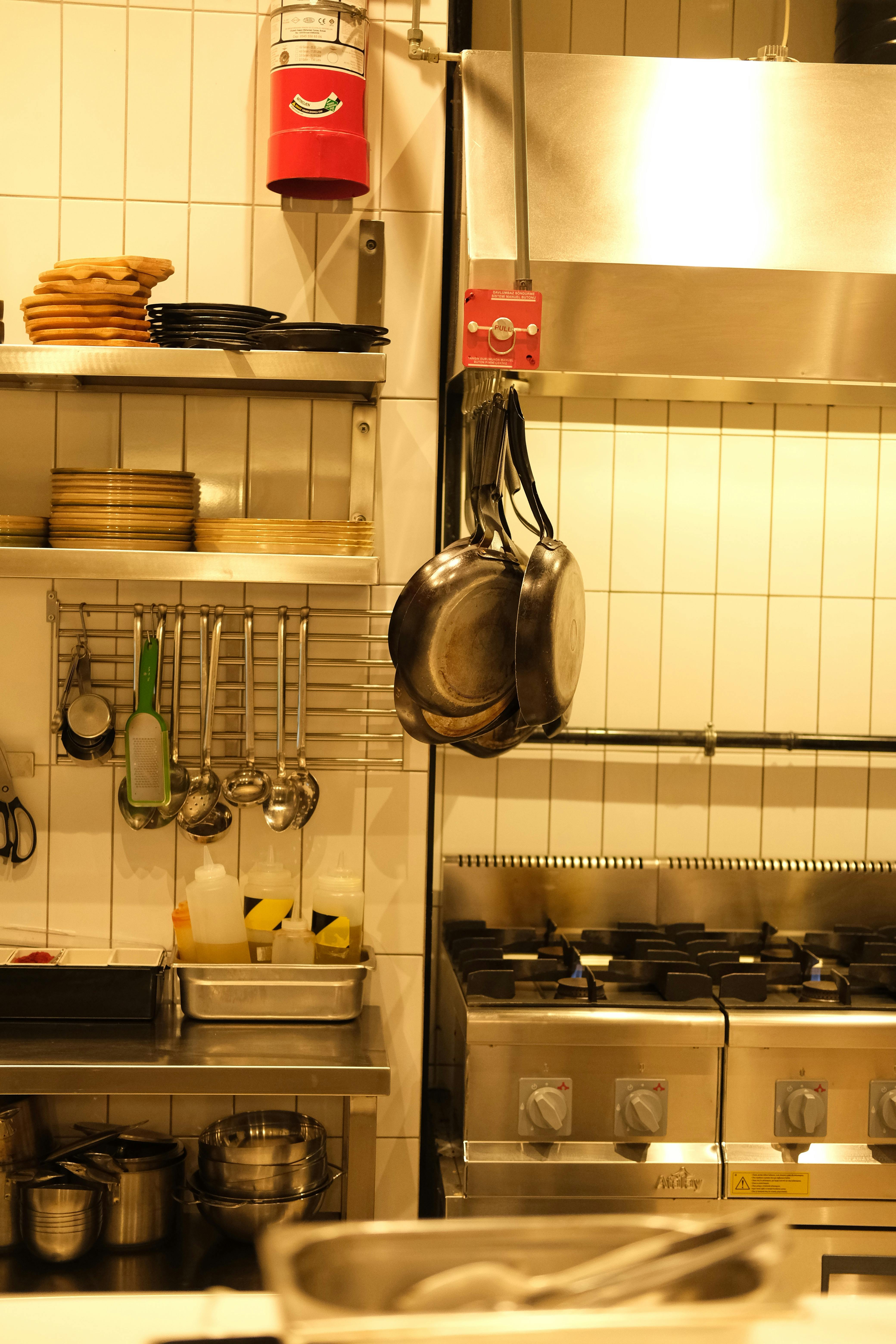 A well-equipped industrial kitchen with hanging pans and cooking utensils.