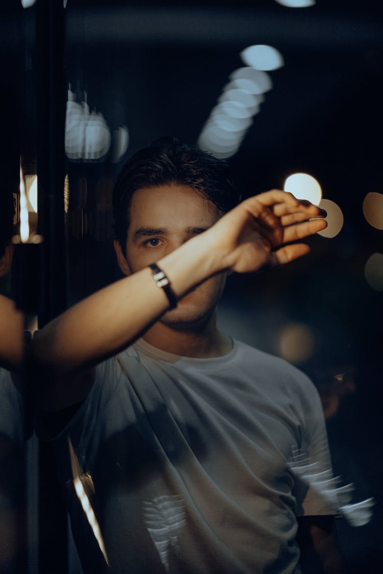 Man In A White T-Shirt With His Arm Covering His Face 