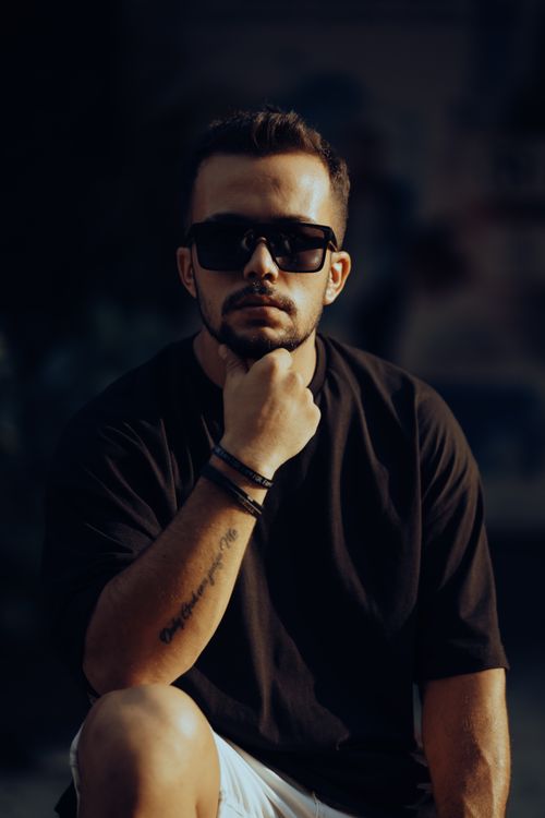 Free Portrait of a stylish man wearing sunglasses and tattoos, set in an outdoor urban environment. Stock Photo