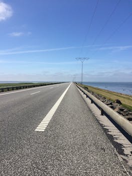 Empty asphalt road on Rømø Island, Denmark, with sea view and open sky.