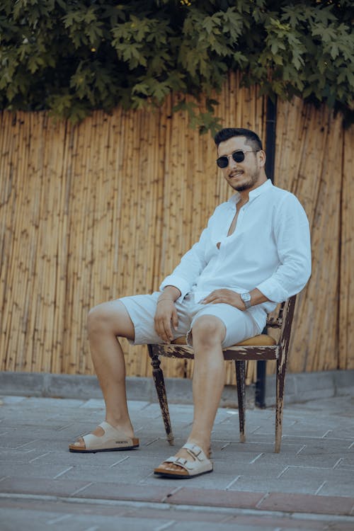 Man in a White Shirt and Shorts Sitting on a Chair · Free Stock Photo